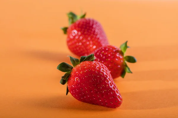 Three juicy strawberry on orange background — Stock Photo, Image