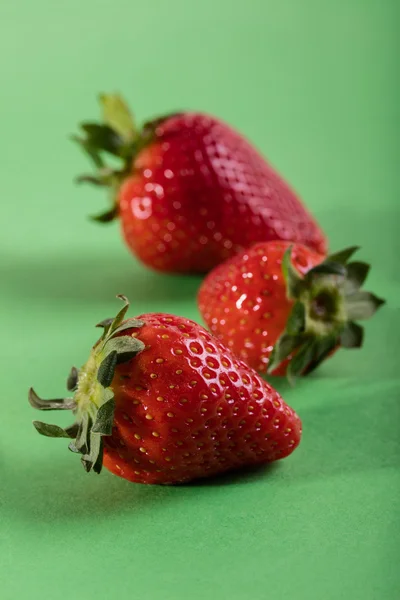 Trois fraises juteuses sur fond vert — Photo