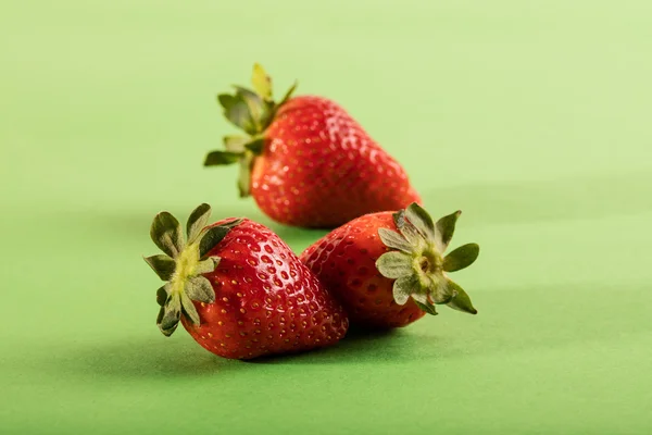 Trois fraises juteuses sur fond vert — Photo