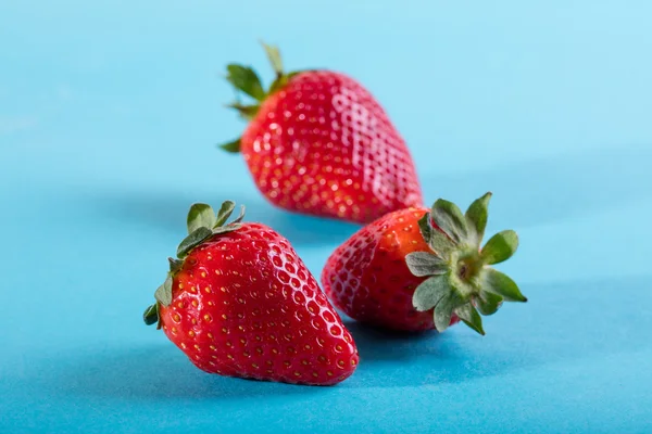 Three juicy strawberry on blue background — Stock Photo, Image