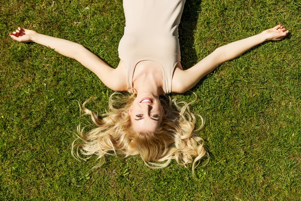 Felice giovane donna sdraiata sull'erba — Foto Stock