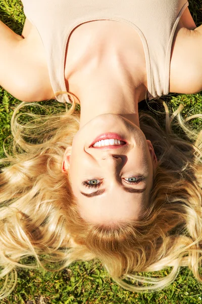 Gelukkig jonge vrouw liggend op het gras — Stockfoto