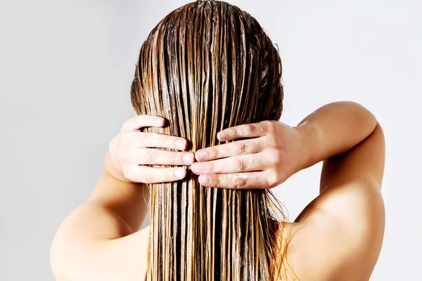 Donna che applica balsamo per capelli. Isolato su bianco. — Foto Stock