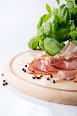 Black forest ham and basil on wooden cutting board clipart