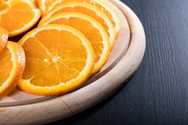 Fatias de laranja na placa de corte de madeira — Fotografia de Stock