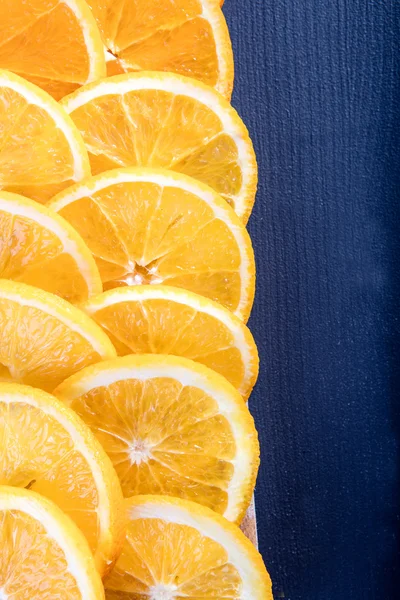 Juicy orange slices on navy blue board — Stock Photo, Image