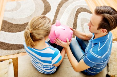 Back view of couple sitting on sofa with piggy bank clipart