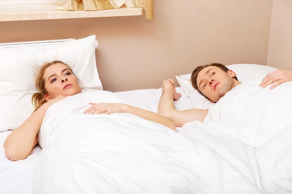Молода ображена пара лежить у ліжку — стокове фото