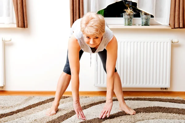 Senior vrouw doet yoga in de woonkamer — Stockfoto