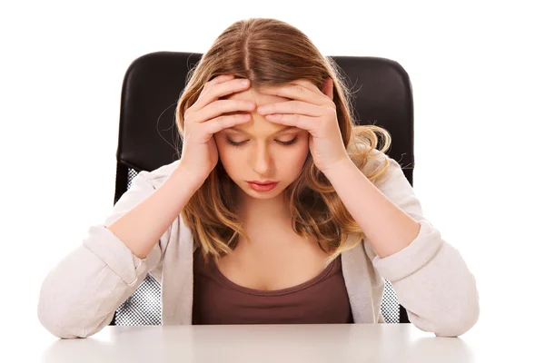 Jeune femme inquiète assise au bureau — Photo