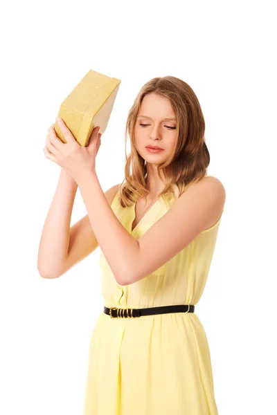 Junge Frau schüttelt den Geschenkkarton — Stockfoto