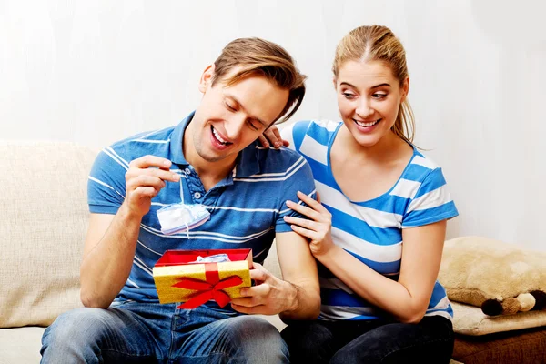 Happy couple - woman hugging her husband who holding gift box and baby shoe Royalty Free Stock Images