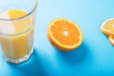 Bardak portakal suyu, yarım portakal ve portakal dilimleri