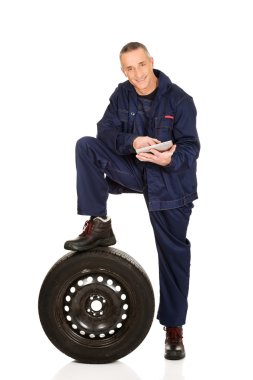 Lastik ve tabletle gülümseyen tamirci.