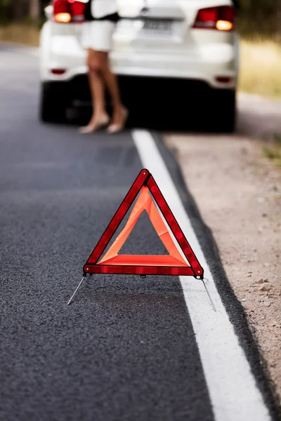 Triângulo de aviso vermelho e carro quebrado no meio de forrest — Fotografia de Stock