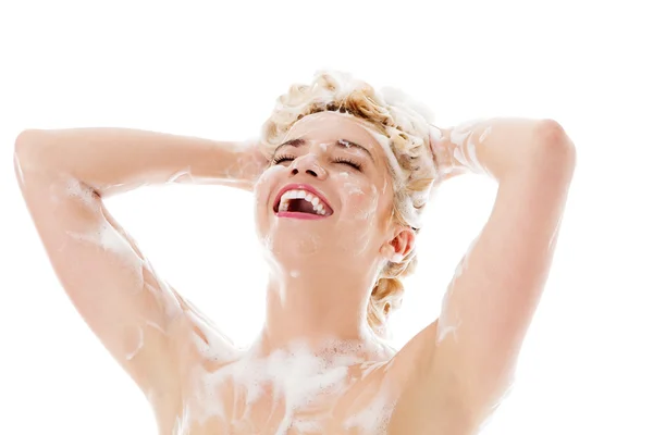 Bella giovane donna sorridente che si lava i capelli con lo shampoo isolato su bianco. — Foto Stock