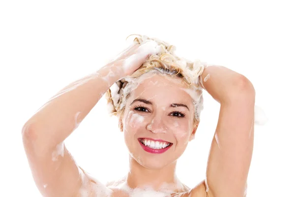 Bela jovem sorridente lavando o cabelo com xampu isolado em branco. — Fotografia de Stock