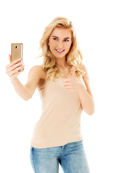 Feliz joven mostrando ok cantar y tomar fotos de sí misma en el teléfono inteligente —  Fotos de Stock
