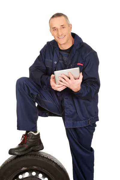 Smiling mechanic with a tire and tablet — Stock Photo, Image