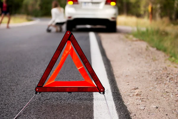 Czerwony trójkąt ostrzegawczy i zepsuty samochód na środku forrest — Zdjęcie stockowe