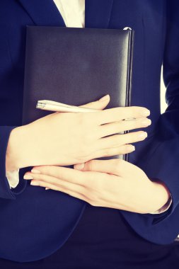 Defter ve kalem kadının elinde.