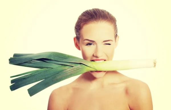 Mooie vrouw met verse groene prei in mond — Stockfoto