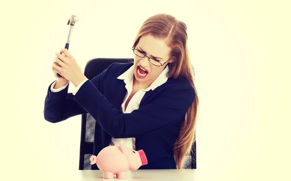 ビジネスの女性は貯金箱を破壊しようとしています。 — ストック写真