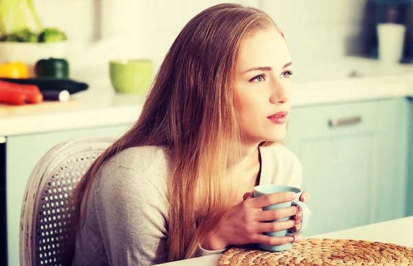 Woman sitting in the kitchen and drinking. — Stock Photo, Image