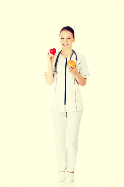 医生抱着健康的葡萄柚和红色的心. — 图库照片