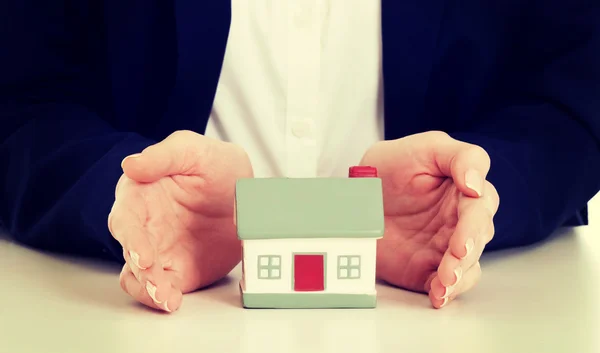 Close up on house model between hands on table. — Stock Photo, Image