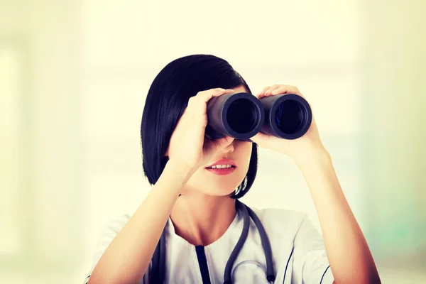 Menina médica atraente olhando através de binóculos — Fotografia de Stock