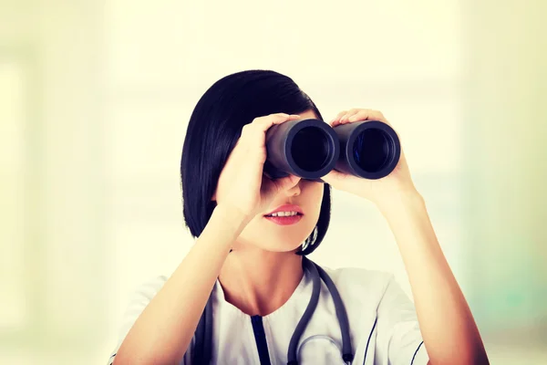 Atractiva chica médica mirando a través de prismáticos —  Fotos de Stock