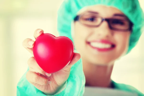 Smiling female doctor or nurse holding heart — Stock Photo, Image