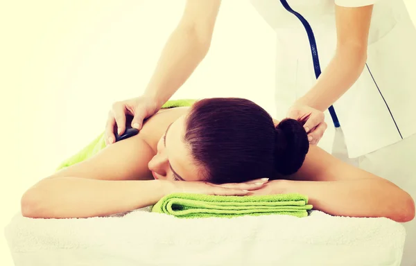 Hermosa mujer tumbada en el salón de spa teniendo masaje de piedra . — Foto de Stock