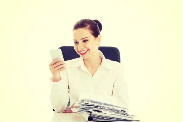 Schöne Geschäftsfrau sitzt an einem Schreibtisch mit einem Stapel Papiere. — Stockfoto