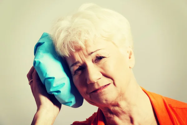 Une vieille dame avec un sac de glace près de sa tête . — Photo