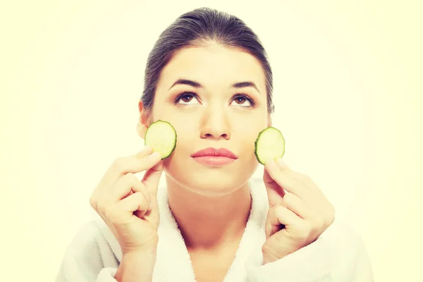 Hermosa mujer en albornoz sosteniendo rebanadas de pepino . — Foto de Stock