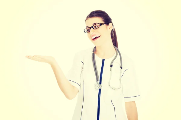 Joven hermosa mujer médico mostrando en el espacio de copia . —  Fotos de Stock