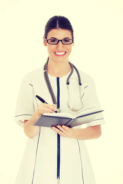 Jovem médico feminino wirting em um livro . — Fotografia de Stock