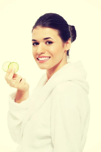 Beautiful woman in bathrobe holding cucumbers. — Stock Photo, Image