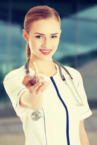 Beautiful nurse or doctor is holding raw garlic. — Stock Photo, Image