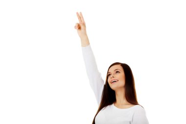 Gülümseyen genç kadın bir şey gösteriyor.