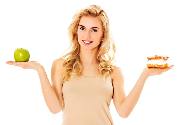Young woman holding an apple and cookie — Stock Photo, Image