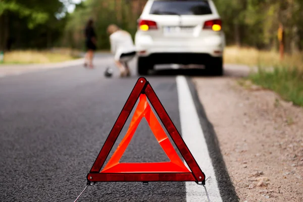 Triángulo rojo de advertencia y coche roto en medio del bosque —  Fotos de Stock