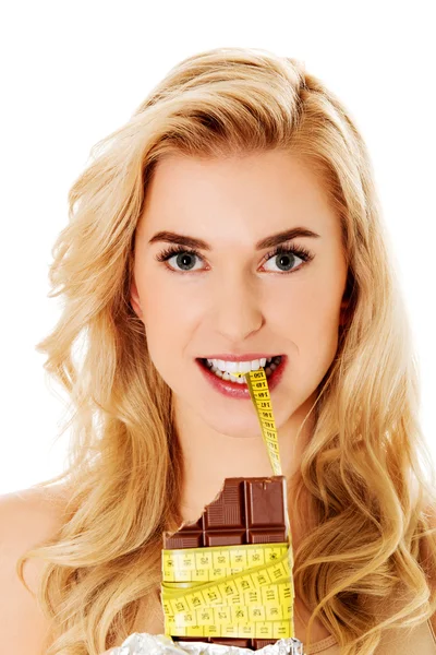 Młoda kobieta trzyma czekoladę i zjada taśmę. — Zdjęcie stockowe