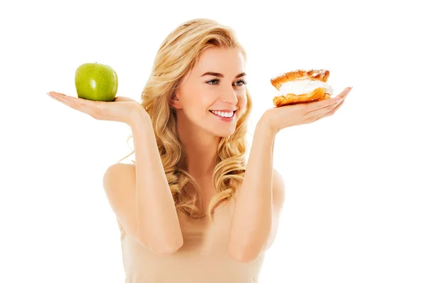 Mujer joven sosteniendo una manzana y una galleta —  Fotos de Stock