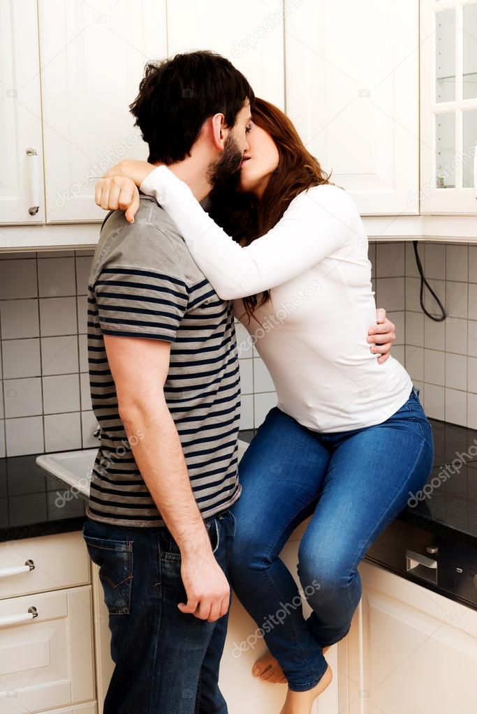 Romantic couple kissing in the kitchen.
