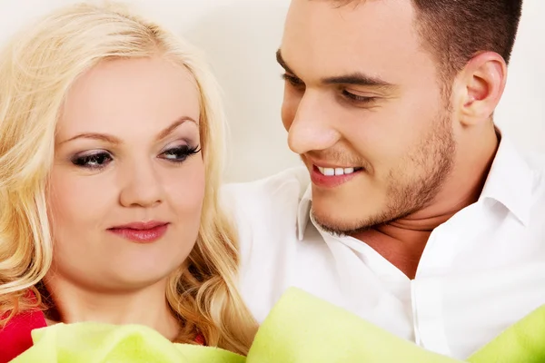 Happy young couple sitting on the couch — Stock Photo, Image