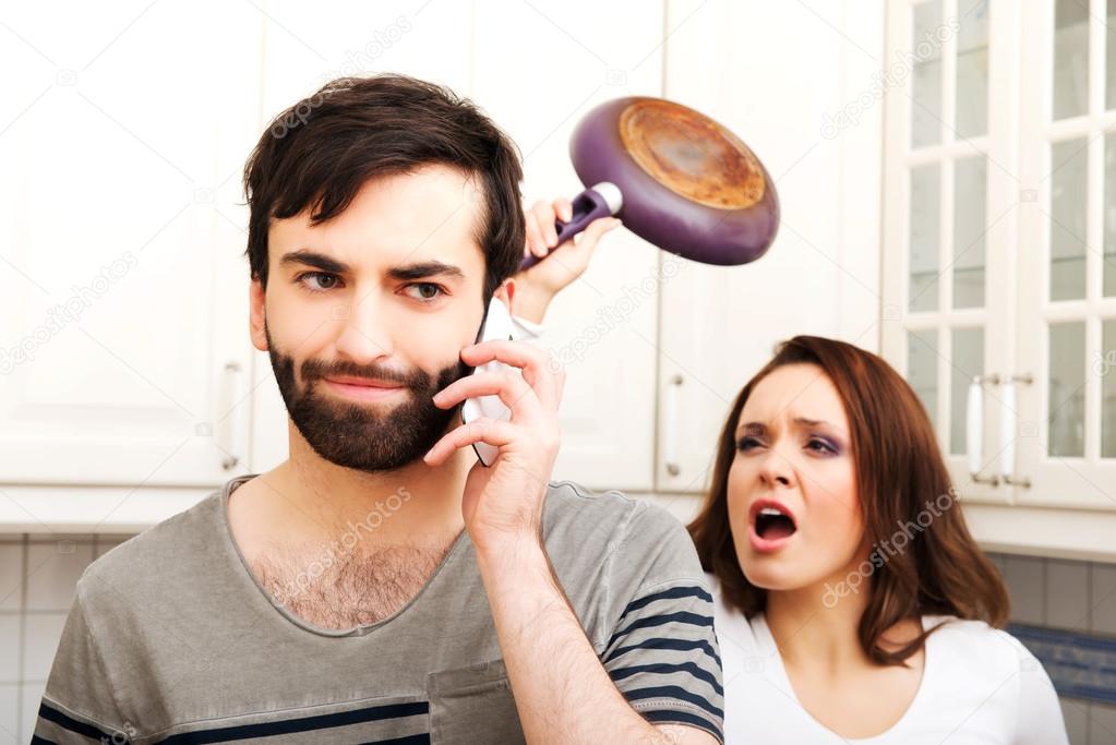 Angry young woman hitting men with frying pan.