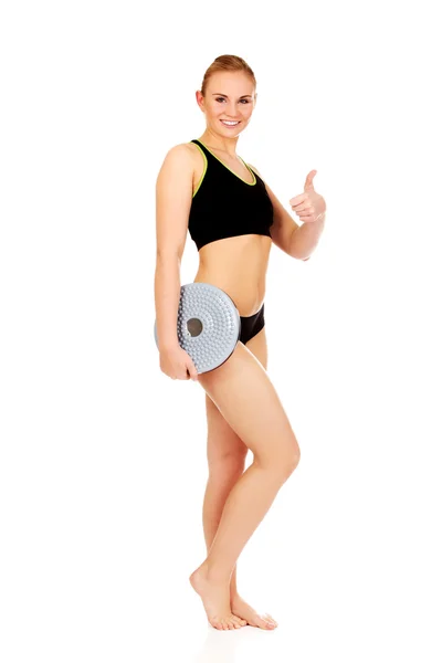 Young athletic woman holding balance board and shows thumb up — Stock Photo, Image